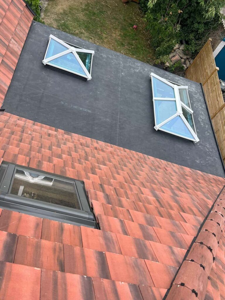 This is a photo taken from the roof ridge looking down a tiled pitched roof on to a flat roof. Works carried out by LJ Roofing Bradford on Avon